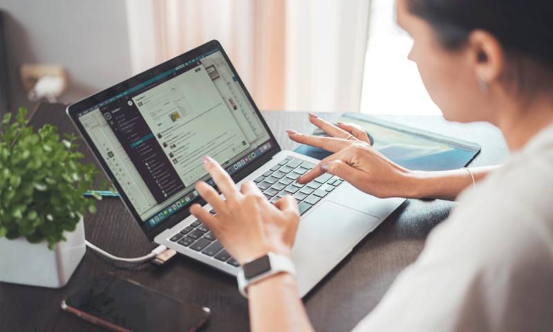 A person working in their laptop, looking at their Slack messages.