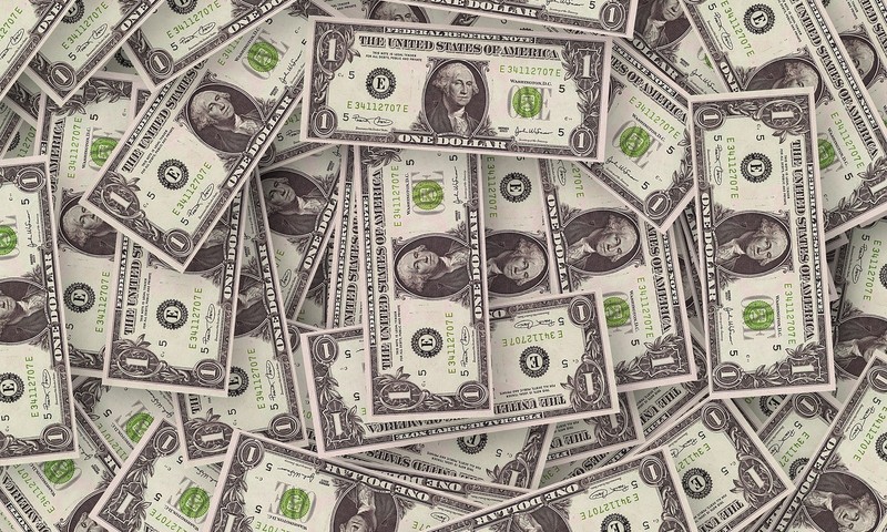 A pile of US one-dollar bills scattered across the frame.